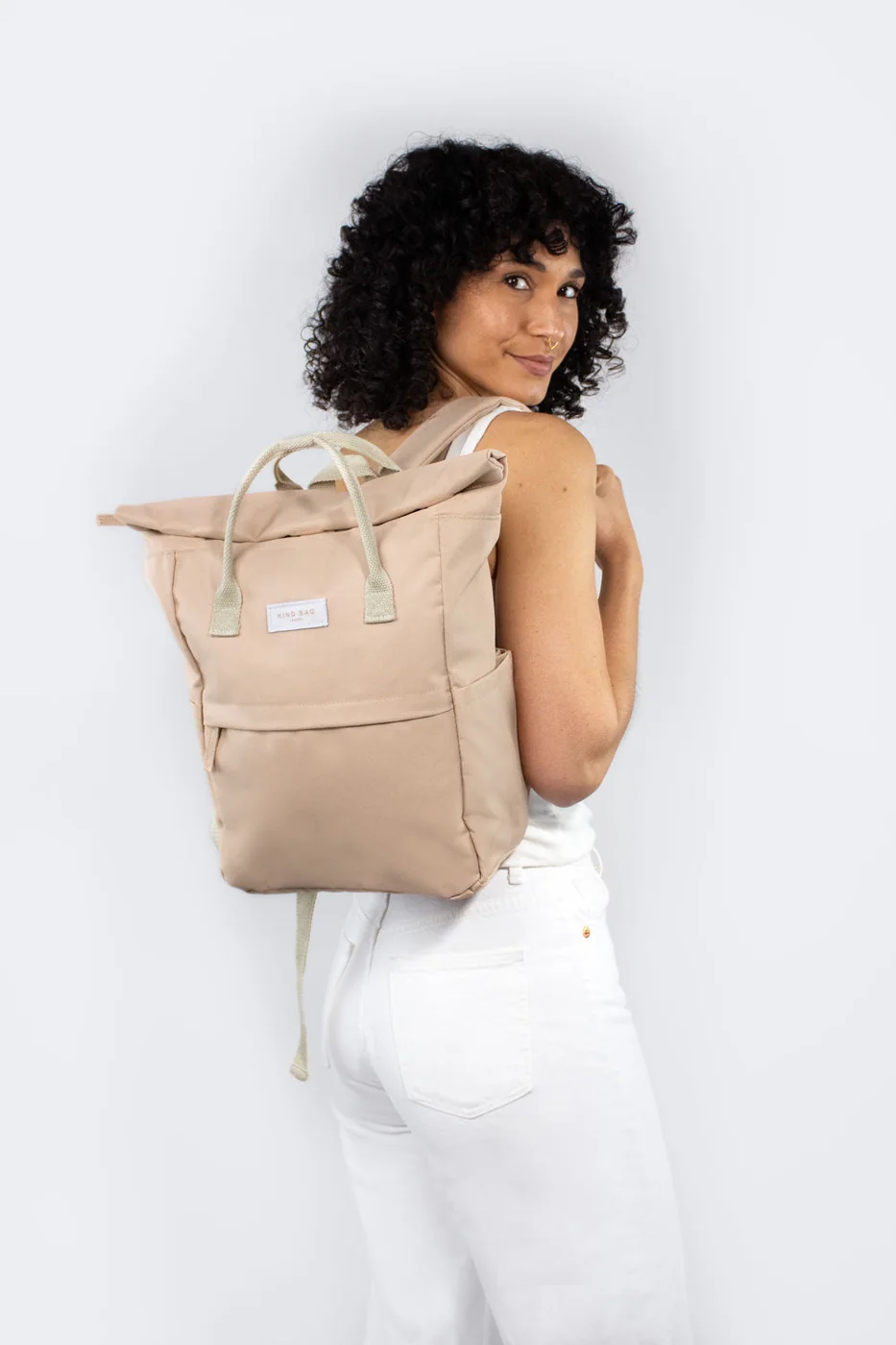 Frau trägt den Kind Bag Backpack Medium in Beige über der Schulter