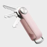 Rückseite des Orbitkey Key Organiser Tracker in Blush, Schlüssel ausgeklappt, Ladekontakt am Tracker-Modul