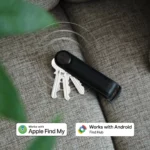 Orbitkey Key Organiser Tracker in Schwarz auf einem Sofa, mit Hinweis auf Apple «Wo ist?» und Google Find Hub