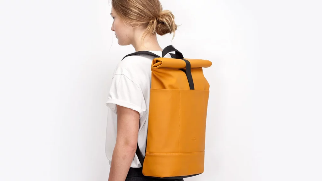 Frau trägt den Ucon Acrobatics Hajo Rolltop-Rucksack in Gelb auf dem Rücken
