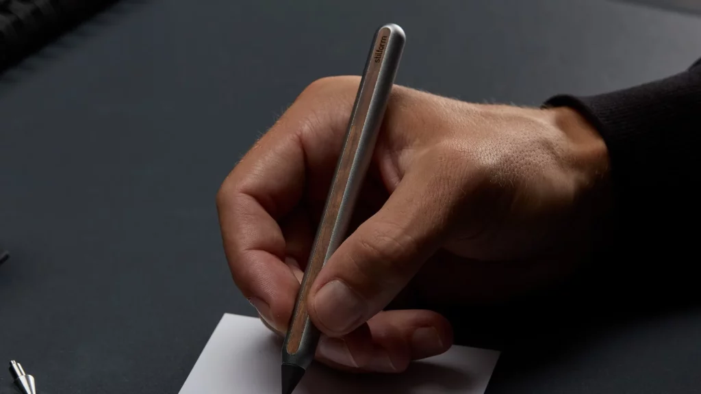 Hand schreibt mit dem Stilform AEON Bleistift aus Aluminium mit Holzfurnier auf Papier