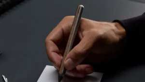 Hand schreibt mit dem Stilform AEON Bleistift aus Aluminium mit Holzfurnier auf Papier