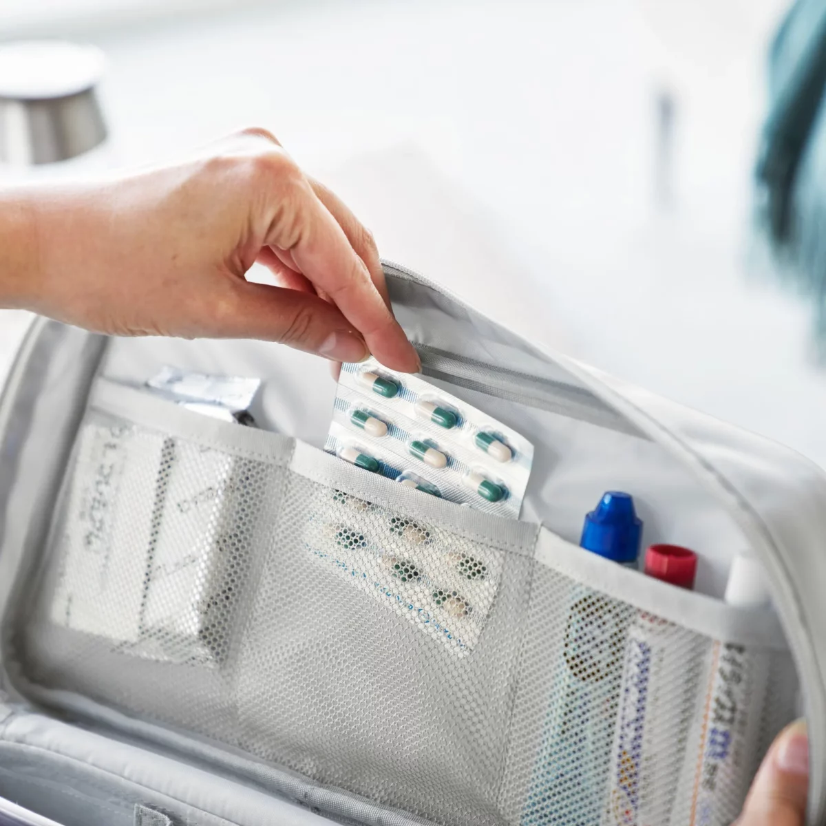 Yamazaki TOWER Storage Pouch with Dividers in Gray; the user can remove pills from the mesh pocket in the lid