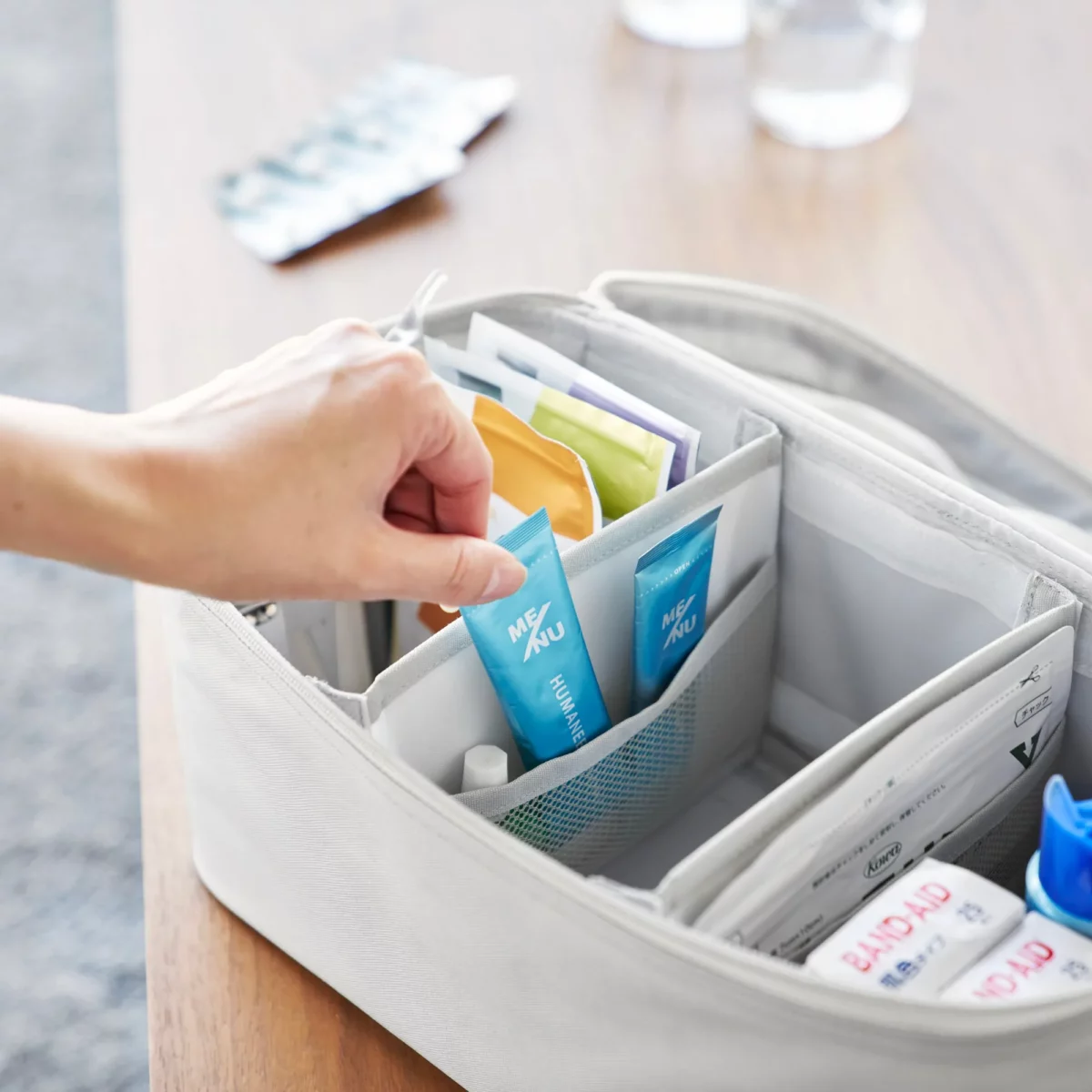 Yamazaki TOWER Storage Bag with Dividers in Gray; a hand reaches for an ointment from the front compartment