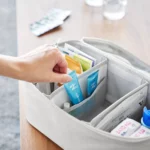 Yamazaki TOWER Storage Bag with Dividers in Gray; a hand reaches for an ointment from the front compartment
