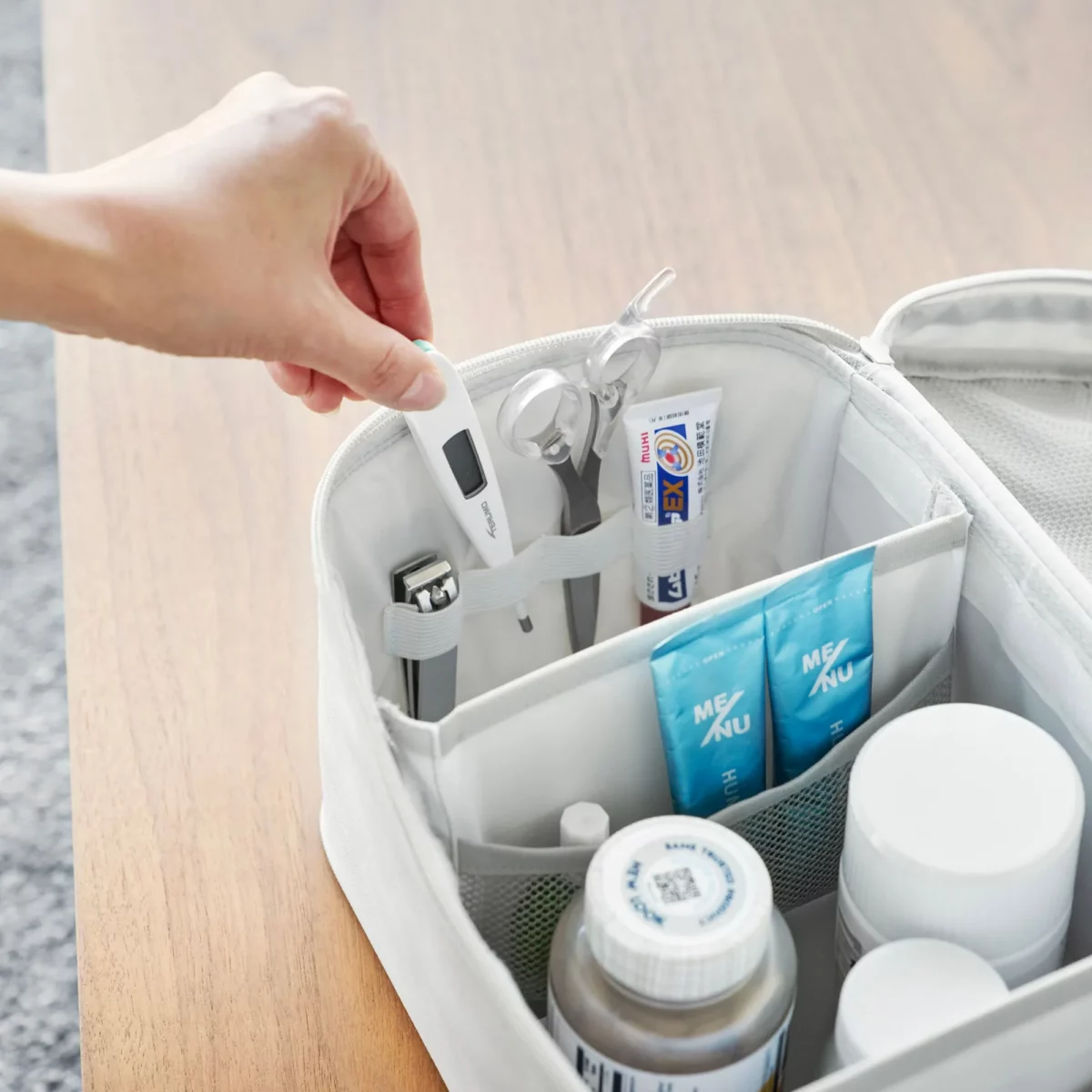 Yamazaki TOWER Storage Bag with Dividers in Gray; a person is inserting a thermometer into the divider compartment