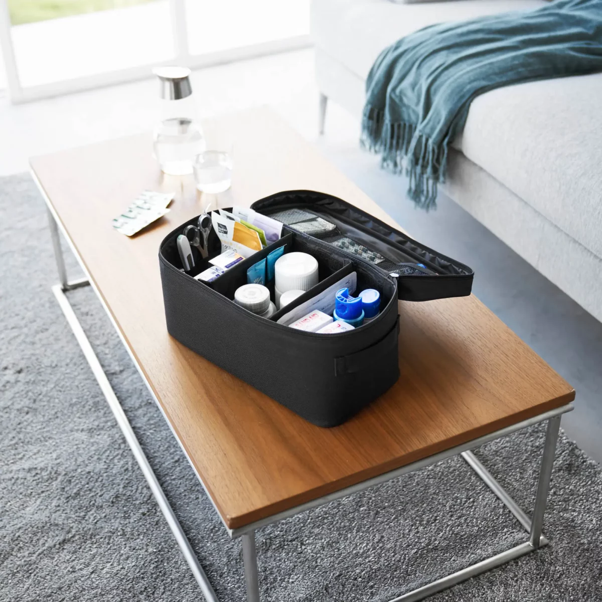 Yamazaki TOWER Storage Bag with Dividers in Black, open on the coffee table with a first-aid kit