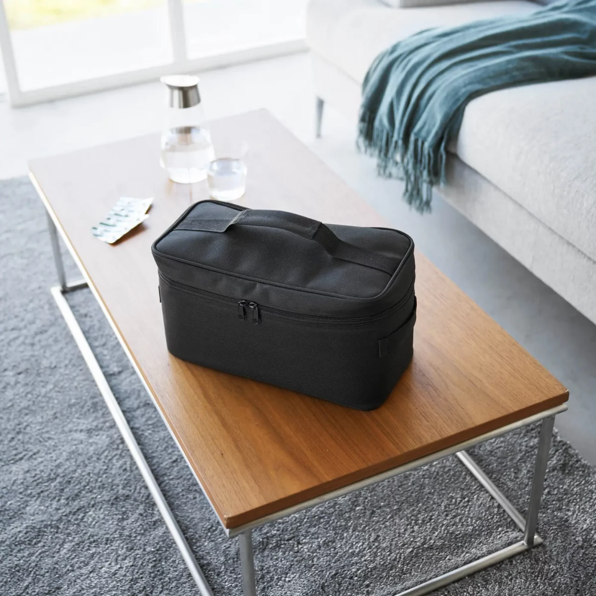 Yamazaki TOWER Storage Bag with Dividers in Black, closed on the coffee table in the living room