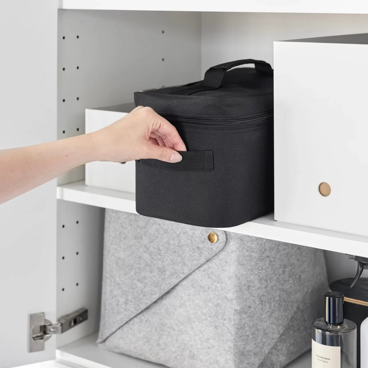 Yamazaki TOWER Storage Bag with Dividers in Black; it is pulled out of the cabinet shelf by the side handle