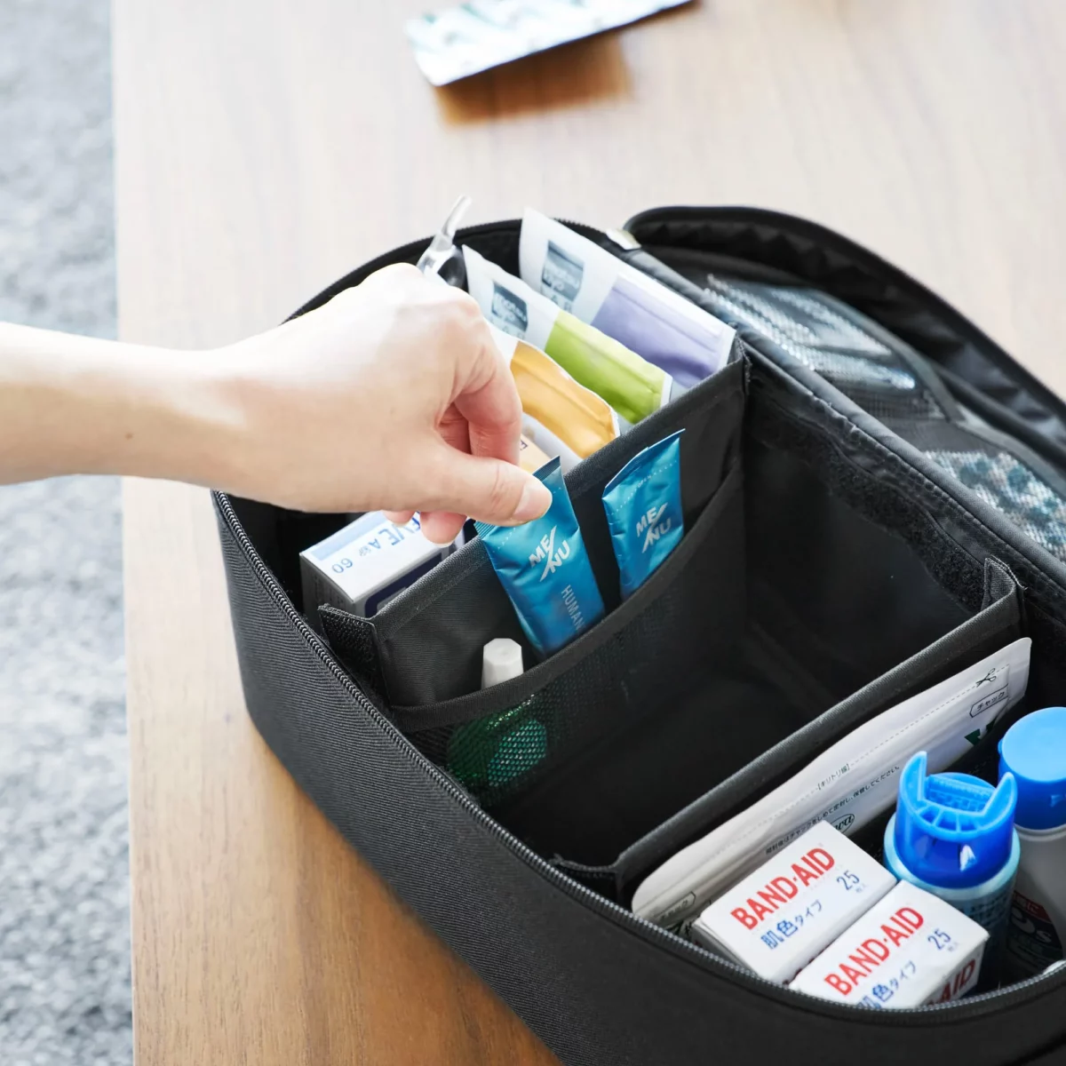 Yamazaki TOWER Storage Pouch with Dividers in Black; a hand reaches for an ointment from the front compartment