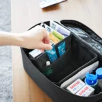 Yamazaki TOWER Storage Pouch with Dividers in Black; a hand reaches for an ointment from the front compartment