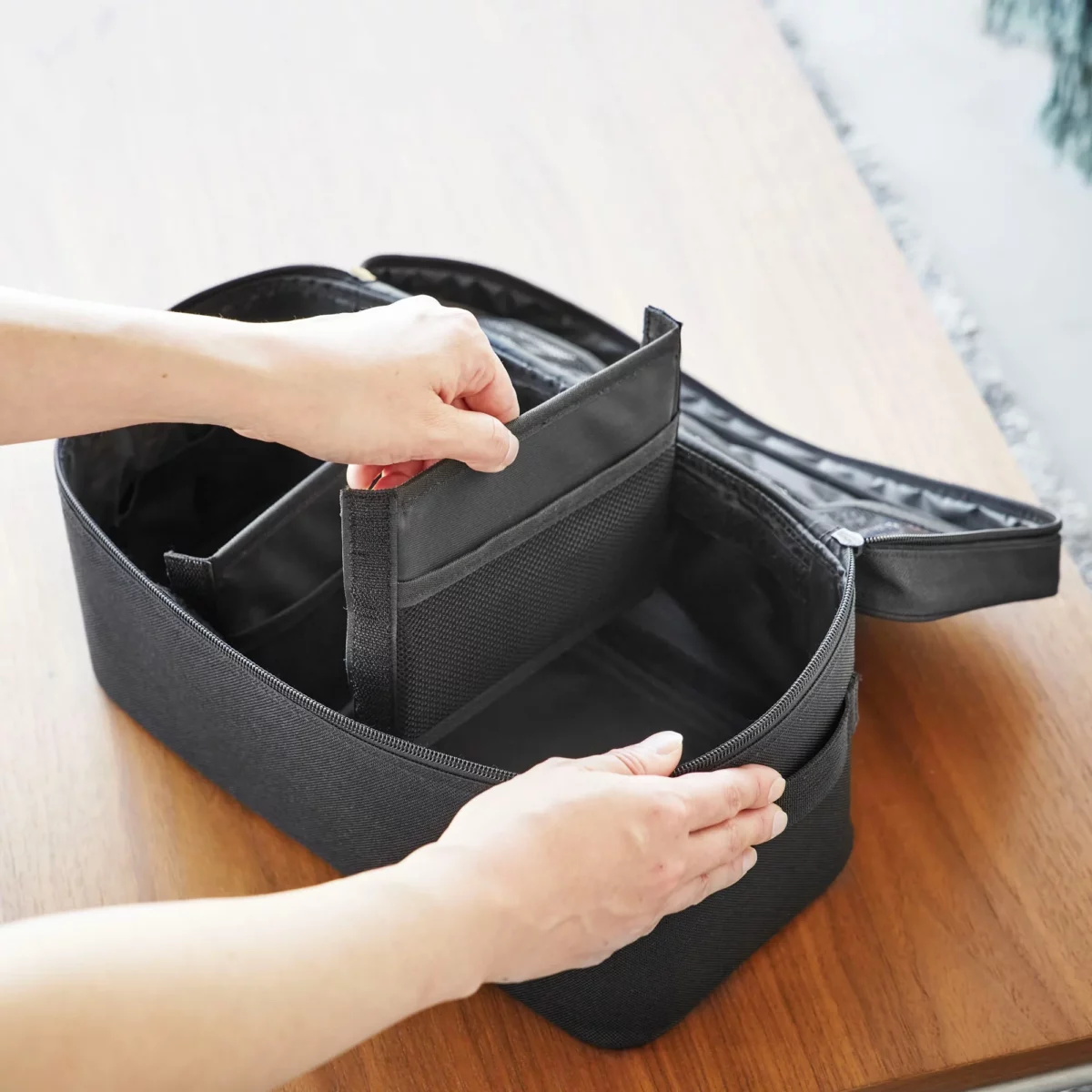 Yamazaki TOWER Storage Bag with Dividers in Black; hands are moving one of the dividers