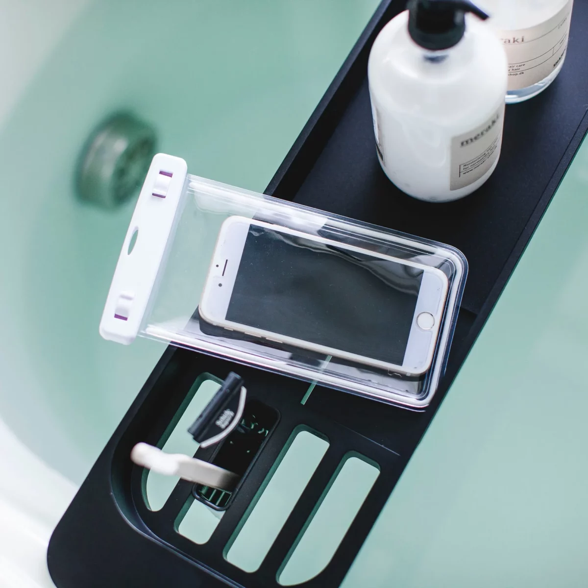 Porte-objets de baignoire Yamazaki TOWER extensible, couleur noire ; gros plan sur les compartiments contenant une brosse à dents et un smartphone