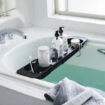Porte-objets extensible TOWER de Yamazaki, noir, posé sur la baignoire avec des bouteilles et une brosse à dents