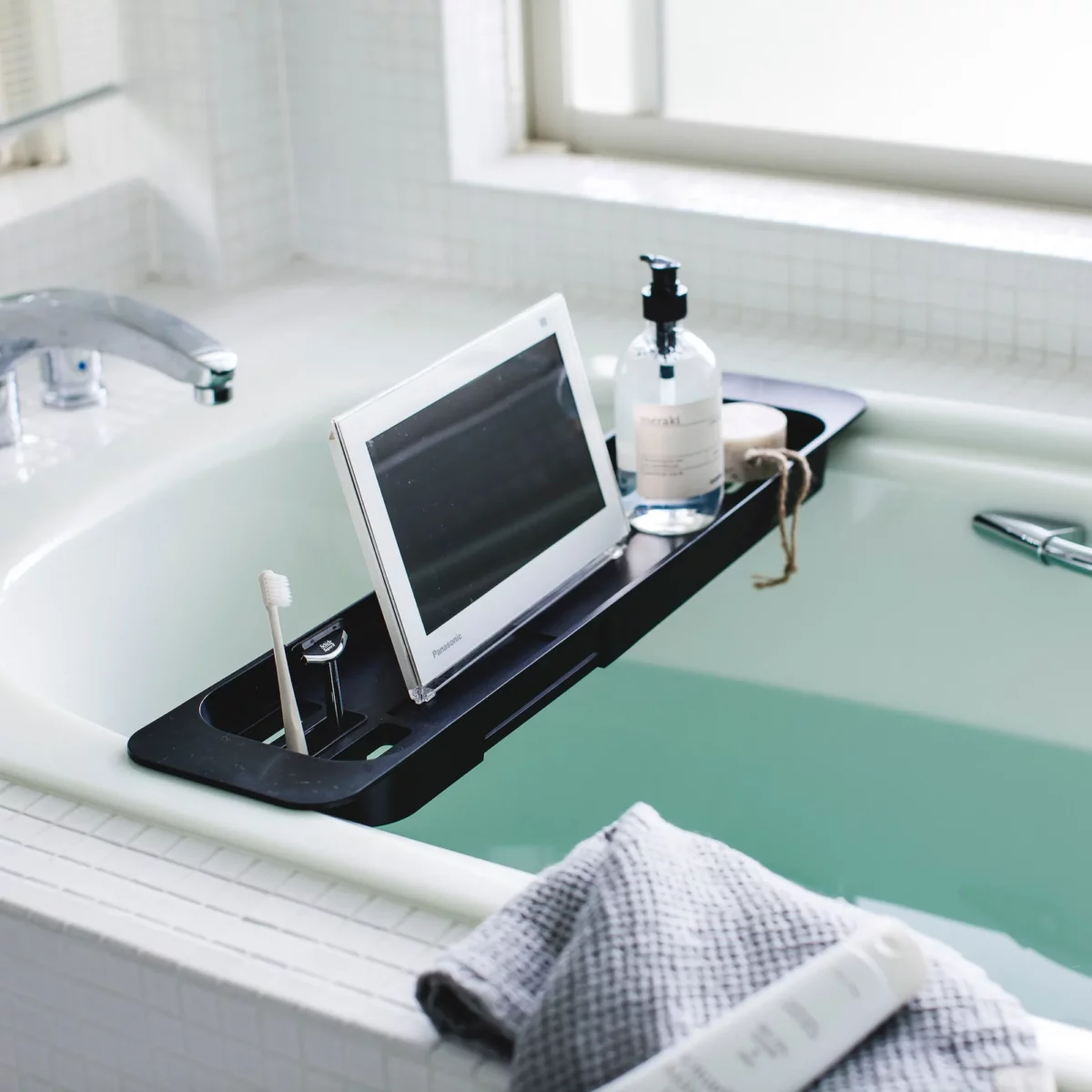 Porte-objets extensible TOWER de Yamazaki pour baignoire, en noir, à poser sur la baignoire, avec tablette et flacon à pompe