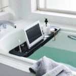 Porte-objets extensible TOWER de Yamazaki pour baignoire, en noir, à poser sur la baignoire, avec tablette et flacon à pompe