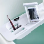 Porte-objets de baignoire Yamazaki TOWER extensible, blanc ; gros plan sur les compartiments avec une brosse à dents et un smartphone