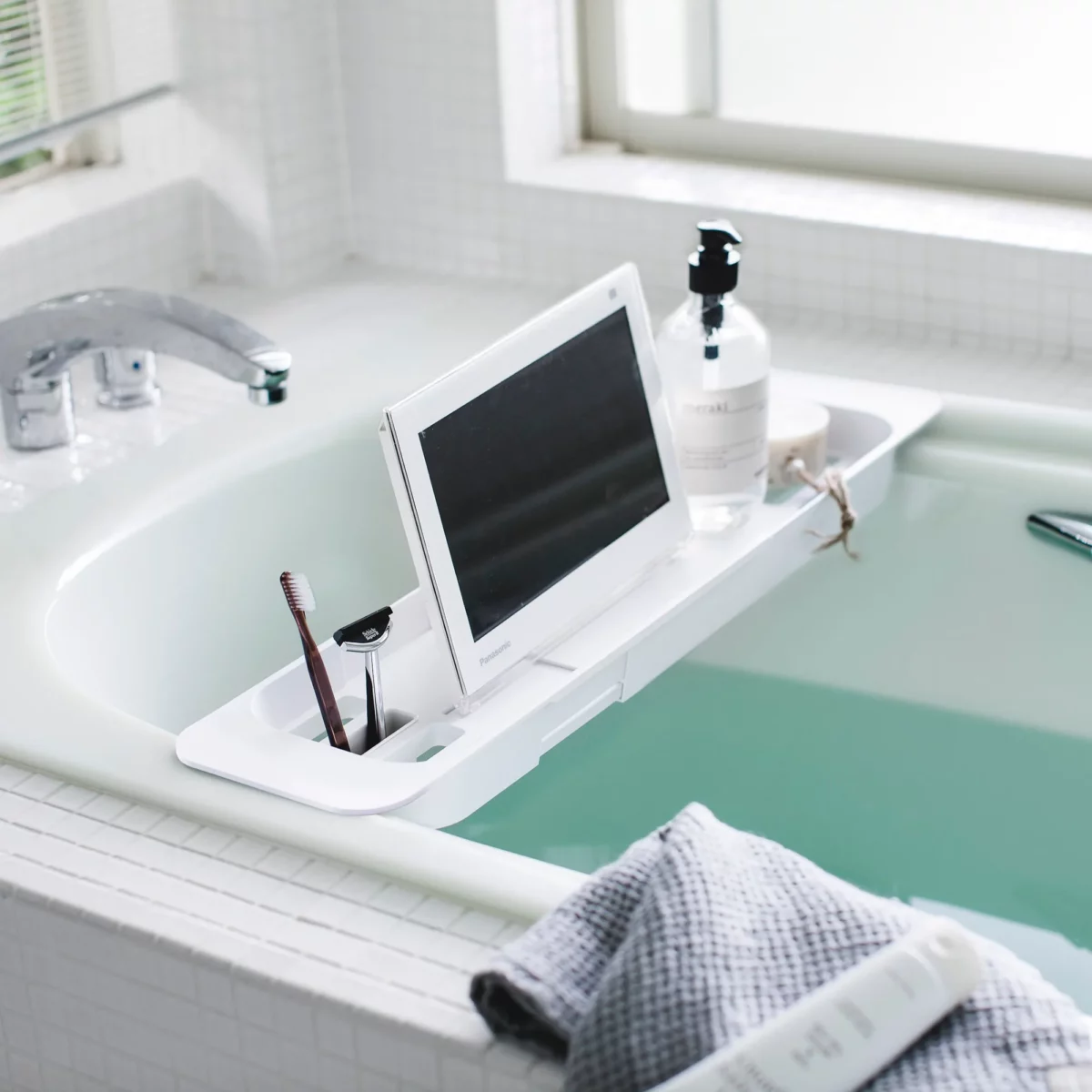 Porte-objets extensible TOWER de Yamazaki pour baignoire, en blanc, à poser sur la baignoire, avec tablette et flacon à pompe