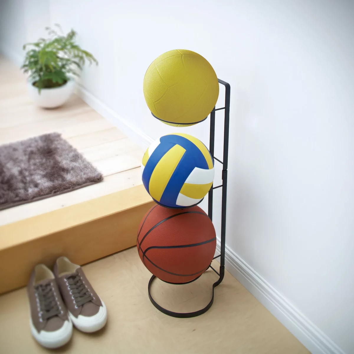 Yamazaki FRAME Ball Stand in Black, with three balls in the entryway next to the shoes