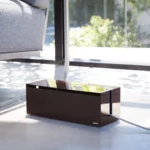 Yamazaki Cable Box WEB in Braun, am Boden neben dem Sofa vor dem Fenster, Kabel seitlich