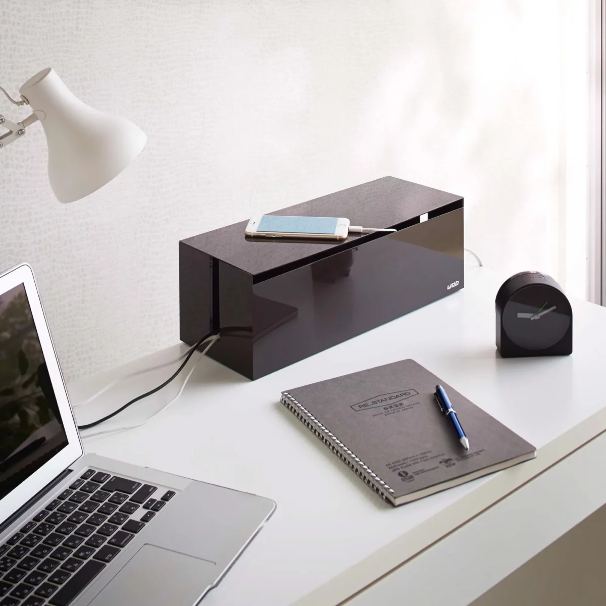 Yamazaki Cable Box WEB in Braun, auf dem Schreibtisch mit Smartphone beim Laden oben