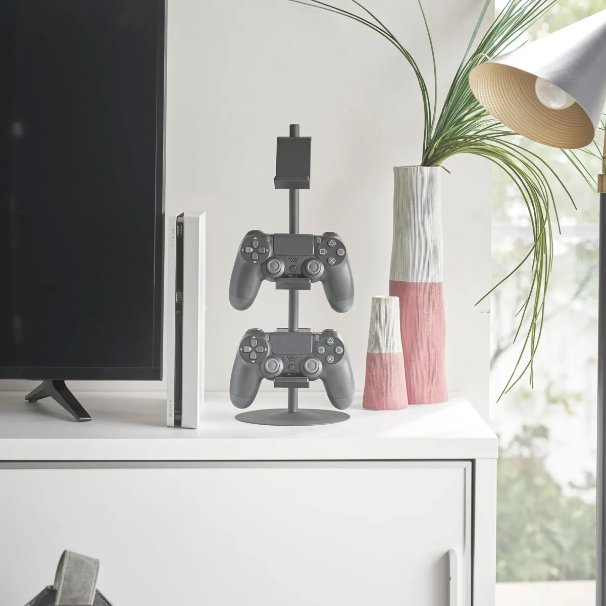 Yamazaki SMART 3-Tier Controller Stand in Black, next to the TV with two controllers