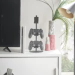 Yamazaki SMART 3-Tier Controller Stand in Black, next to the TV with two controllers