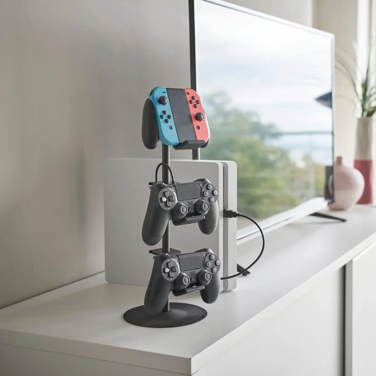 Yamazaki SMART 3-Tier Controller Stand in Black, next to the console with three controllers