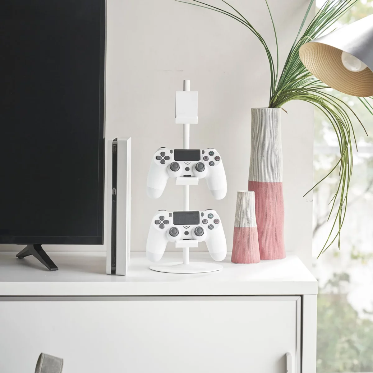 Yamazaki SMART 3-Tier Controller Stand in White, next to the TV with two controllers