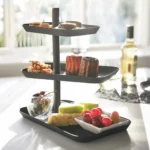 Yamazaki Etagere TOWER 3-stöckig drehbar in Schwarz, schräg am Tisch mit Gebäck neben Weisswein