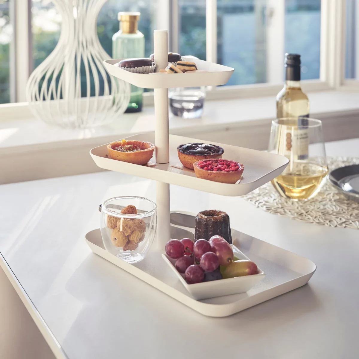 Yamazaki Etagere TOWER 3-stöckig drehbar in Weiss, schräg am Tisch mit Gebäck neben Weisswein