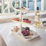 Yamazaki Etagere TOWER 3-stöckig drehbar in Weiss, schräg am Tisch mit Gebäck neben Weisswein