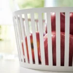 Yamazaki Früchteschale TOWER tief in Weiss, Seitenansicht mit Äpfeln hinter den Stäben