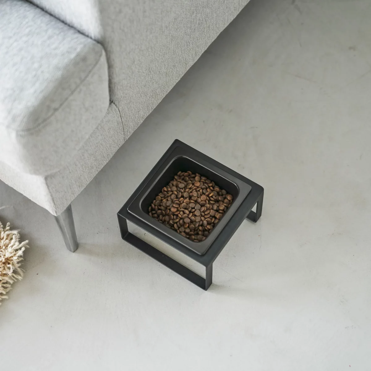 Yamazaki TOWER Food Bowl, single, with stand in black, shown from above next to the sofa with food in the bowl