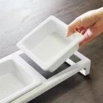 Yamazaki Futternapf TOWER mit Ständer in Weiss, Hand hebt einen Keramiknapf aus dem Ständer