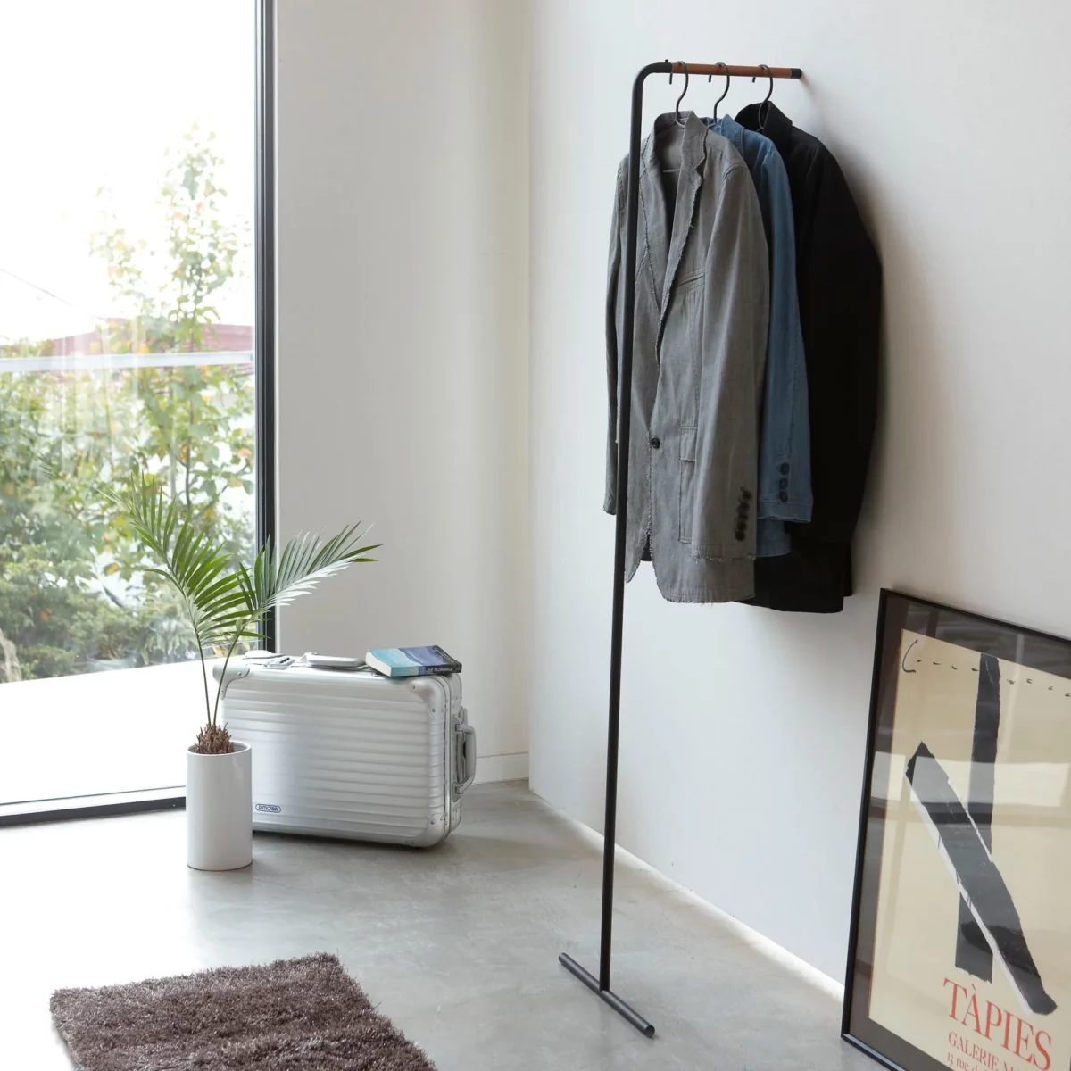 Yamazaki Garderobe TOWER schlank zum Anlehnen in Schwarz, an die Wand gelehnt mit Sakkos neben dem Fenster