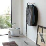 Yamazaki Garderobe TOWER schlank zum Anlehnen in Schwarz, an die Wand gelehnt mit Sakkos neben dem Fenster