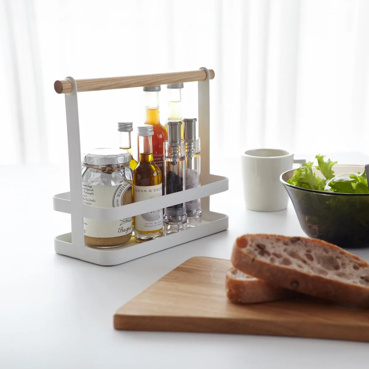 Étagère à épices Yamazaki TOSCA avec poignée en bois, de couleur blanche ; gros plan sur des bouteilles de vinaigre et d'huile posées sur la table