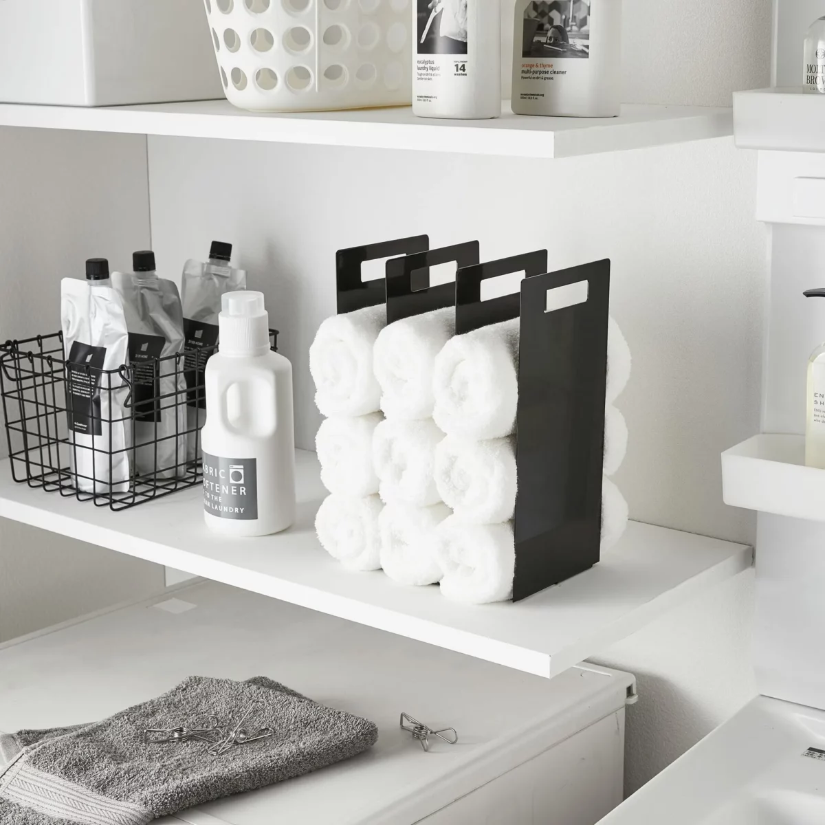 Yamazaki TOWER Towel Storage, 2-Piece Set in Black, with rolled towels on the laundry room shelf