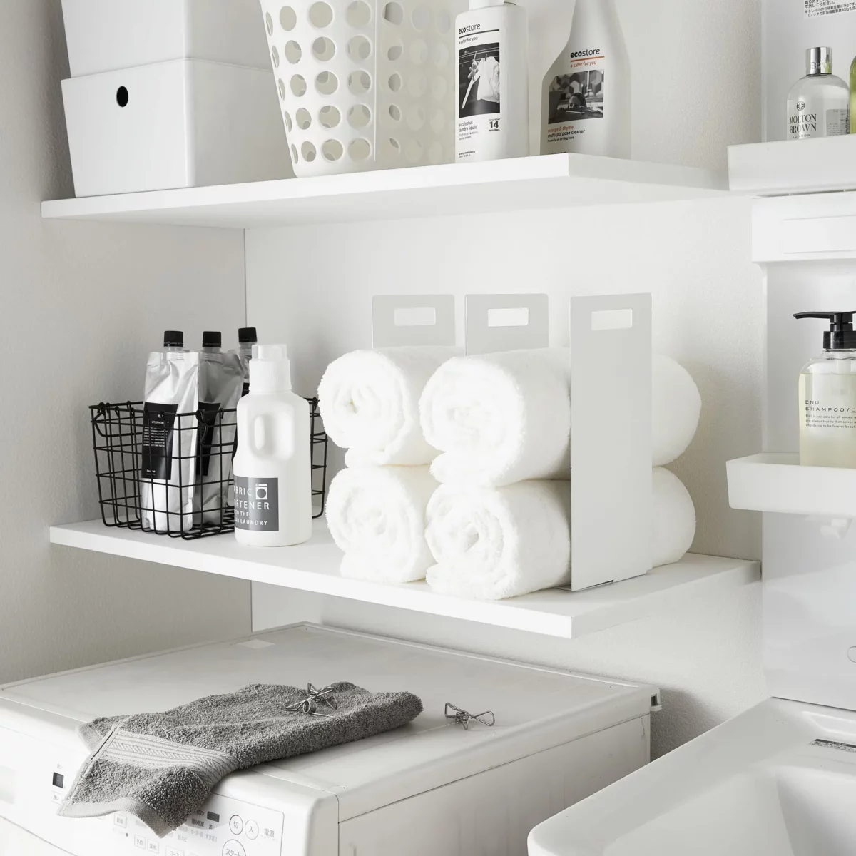 Yamazaki TOWER Towel Storage, Set of 2 in White, on the shelf next to the laundry detergent and wire basket, wide view