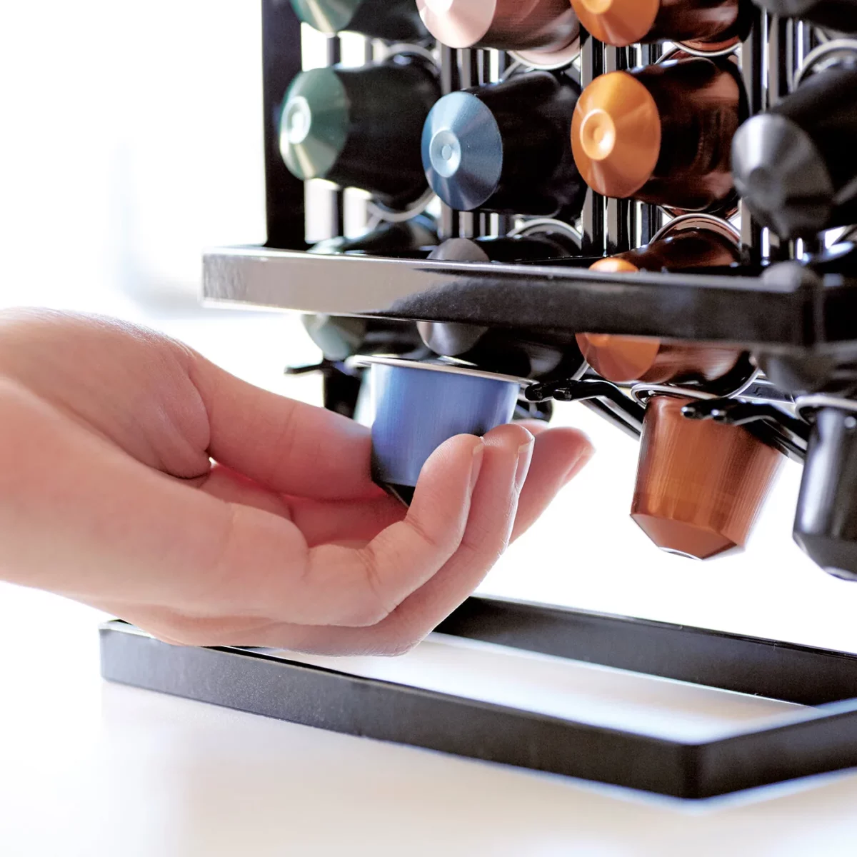 Yamazaki Kaffeekapselhalter TOWER in Schwarz, Hand nimmt unten eine Kapsel heraus