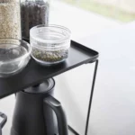Yamazaki Klappregal TOWER stapelbar L in Schwarz, Nahaufnahme mit Glasdosen über dem Wasserkocher