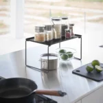 Yamazaki Klappregal TOWER stapelbar M in Schwarz, auf der Arbeitsfläche mit Gläsern über einem Topf