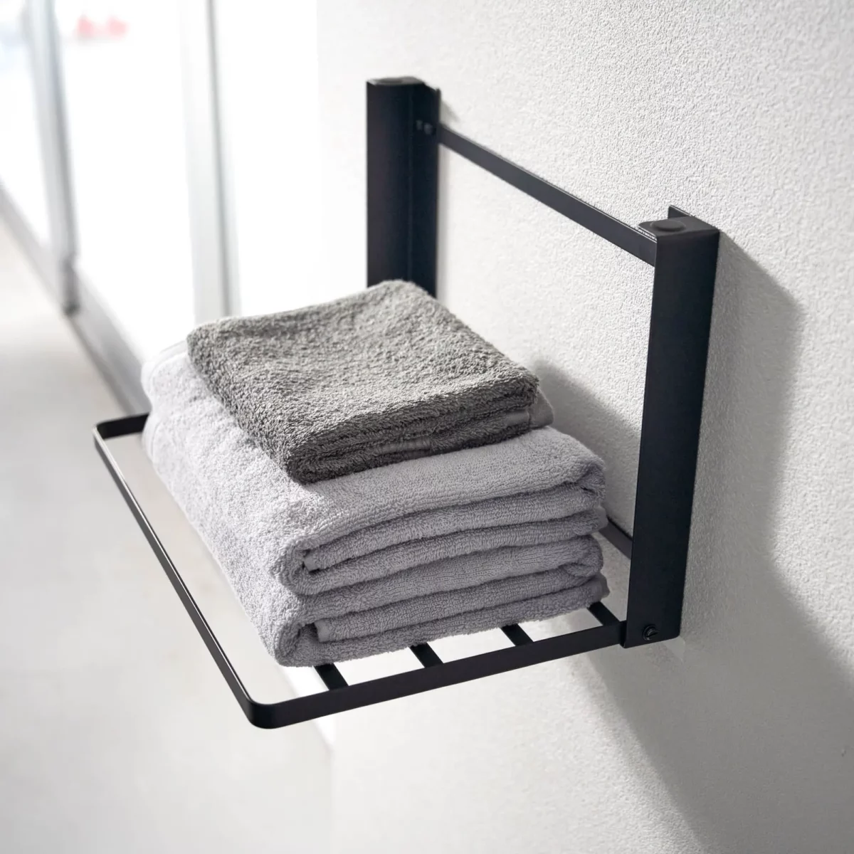 Yamazaki TOWER Folding Wall Shelf in Black, close-up with towels on the steel struts