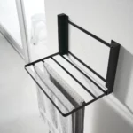Yamazaki TOWER Folding Wall Shelf in Black; a towel hangs over the supports to dry