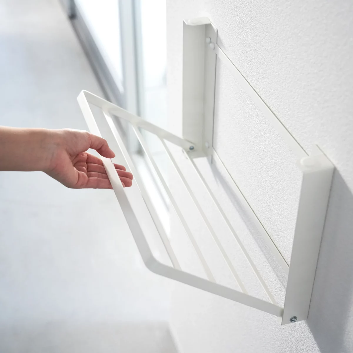 Yamazaki TOWER Folding Wall Shelf in White; the shelf folds down from the wall by hand