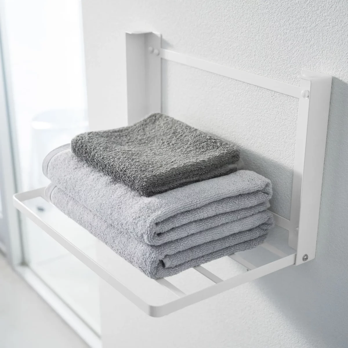Yamazaki TOWER Folding Wall Shelf in White, close-up with towels on the steel struts