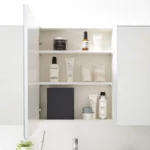 Boîte à crochets adhésifs Yamazaki TOWER avec couvercle, de couleur noire, dans l'armoire à miroir, entre les produits de soin