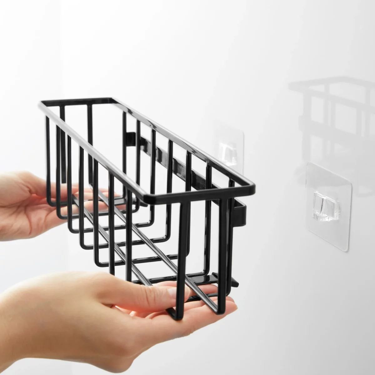 Yamazaki TOWER Film Hook multi-use basket L in black, hands placing the basket onto the adhesive hook