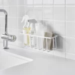 Yamazaki TOWER Film Hook multi-use basket L in white, on a tiled wall next to the sink with spray bottles